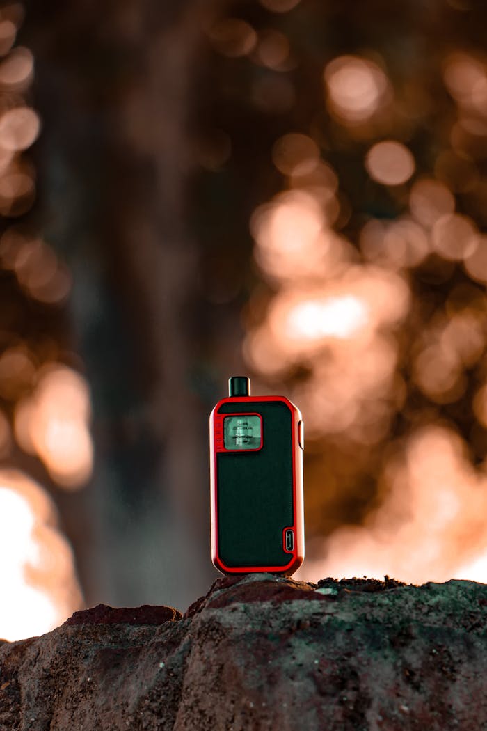 Home A modern vape device on a rock against a blurred, bokeh background, capturing the essence of technology.